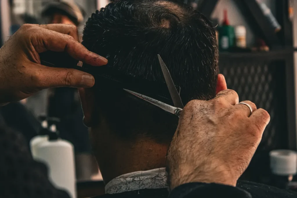 Close view of a barber using scissors on dark hair